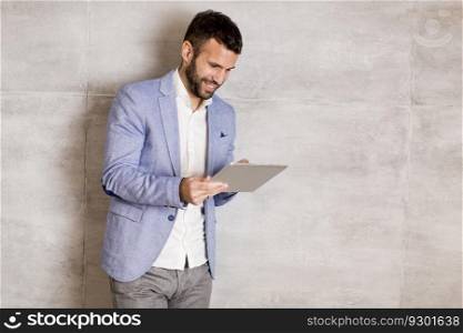 Handsome young man with tablet by the grey wall