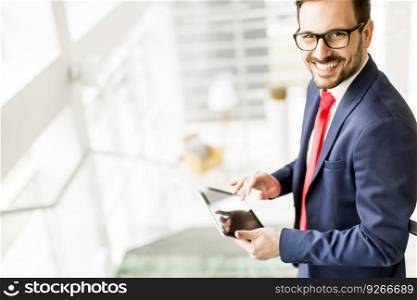 Handsome young man with tablet on stairs in modern office