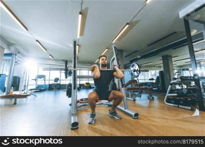 Handsome young man working out with barbells in the gym