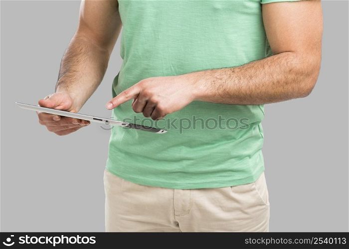 Handsome young man working with a tablet, isolated over gray background