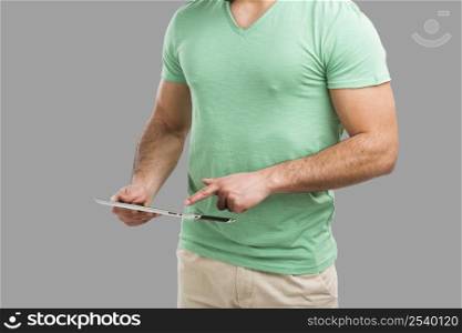 Handsome young man working with a tablet, isolated over gray background