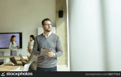 Handsome young modern businessman using digital tablet in the office