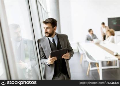 Handsome young modern businessman using digital tablet in the office
