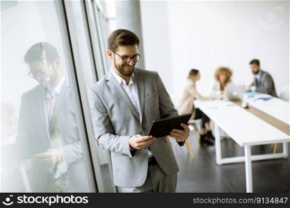 Handsome young modern businessman using  digital tablet in the office