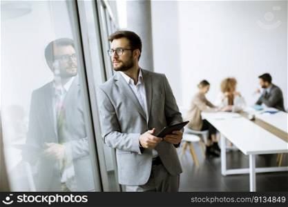 Handsome young modern businessman using  digital tablet in the office