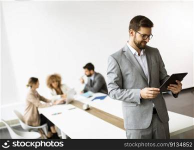 Handsome young modern businessman using digital tablet in the office