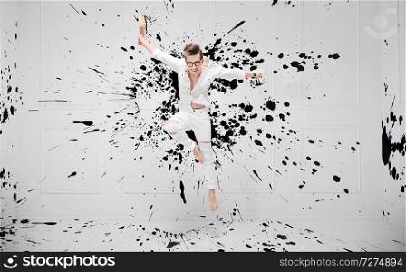 Handsome young painter splashing with black paint