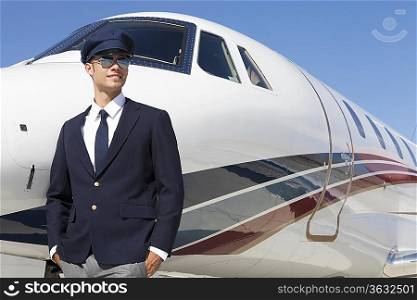 Handsome young pilot standing by private airplane