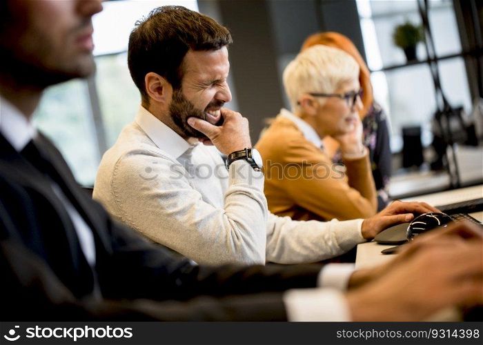 Handsome young professional businessman under stress uses a computer for work in the modern office