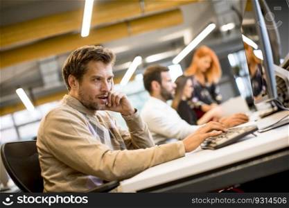 Handsome young professional businessman uses a computer for work in the modern office