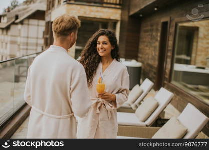 Handsome young  relaxing on the outdoor terrace and drinking fresh orange juice