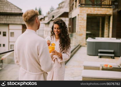 Handsome young  relaxing on  the outdoor terrace and drinking fresh orange juice