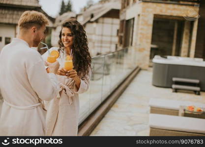 Handsome young  relaxing on the outdoor terrace and drinking fresh orange juice