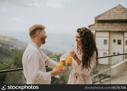 Handsome young  relaxing on the outdoor terrace and drinking fresh orange juice