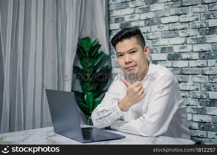 Handsome young smiling businessman working at home with laptop on desk
