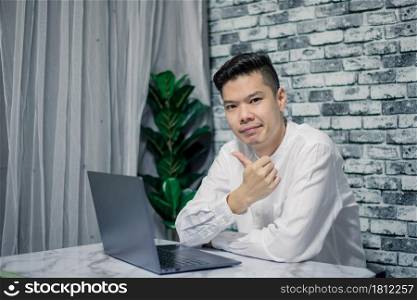Handsome young smiling businessman working at home with laptop on desk
