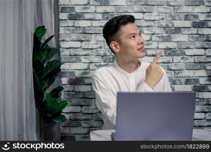 Handsome young thinking while serious working at home with laptop on desk