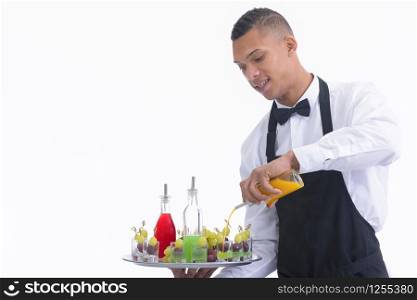 Handsome young waiter holding a tray and mixing liquor into glass shots with grapes. Service and vegan cocktails concept.. Waiter mixing liquor in glass shots with grapes