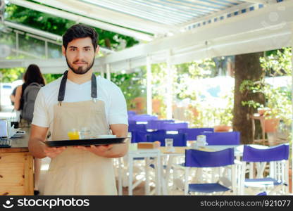 Handsome young waiter holding tray at the coffee shop. Service concept