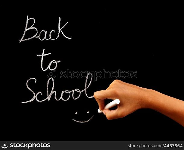 "Handwriting phrase "back to school" on blackboard in classroom, conceptual image of school time, teacher arm holding chalk and writing word, education and knowledge concept"