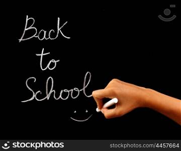 "Handwriting phrase "back to school" on blackboard in classroom, conceptual image of school time, teacher arm holding chalk and writing word, education and knowledge concept"