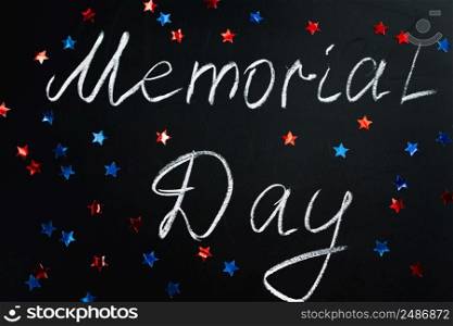Handwritten inscription Memorial Day on a black chalkboard and American blue and red stars on the background. Holiday concept.. Handwritten inscription Memorial Day on a black chalkboard and American blue and red stars on background. Holiday concept.