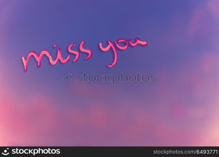 Handwritten phrase miss you on the pink and purple blur background, enjoying relationships, affection and first love concept, happy Valentines day holiday. Miss you after each date