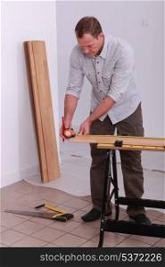 handyman measuring a wooden board with a measure-tape