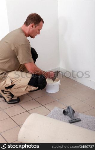 handyman putting glue and laying carpet