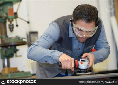 handyman using electric sander with safety glasses