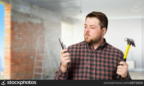 Handyman with hammer and nails in interior. Mixed media. Home renovation and repair