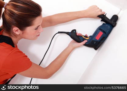 handywoman drilling a hole in the ceiling