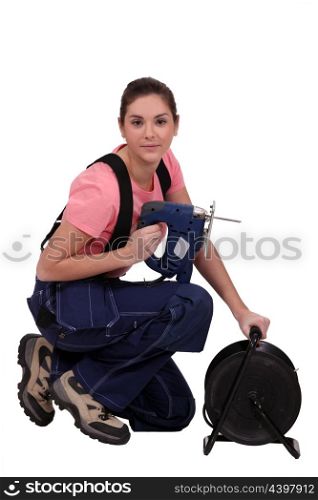 Handywoman holding a jigsaw and an extension cord