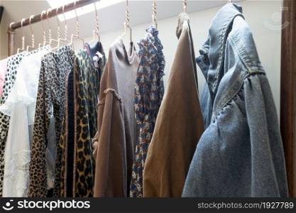 Hangers on rack with colorful stylish fashion clothes in modern room. House interior, fashion and storage concept beauty. Hangers on rack with colorful stylish fashion clothes in modern room. House interior, fashion and storage concept