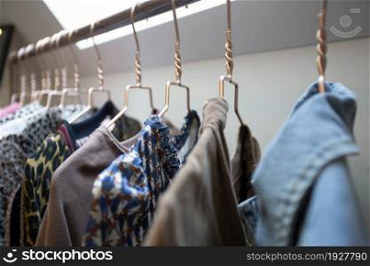 Hangers on rack with colorful stylish fashion clothes in modern room. House interior, fashion and storage concept beauty. Hangers on rack with colorful stylish fashion clothes in modern room. House interior, fashion and storage concept