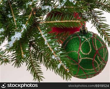 Hanging Christmas balls on a snow-covered branch and falling snow