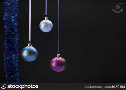 Hanging colorful christmas balls on black background. Hanging three colorful christmas balls on black background