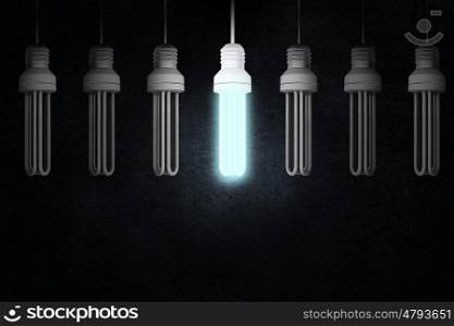 Hanging light bulb. Illuminating hanging light bulb on dark background