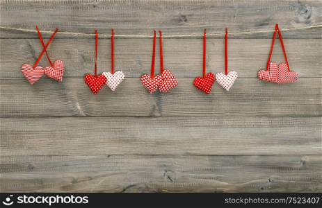 Hanging textile hearts on wooden texture. Valentines day background