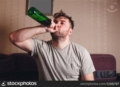 Hangover after hard drinking. Alcohol addicted man with bottle.
