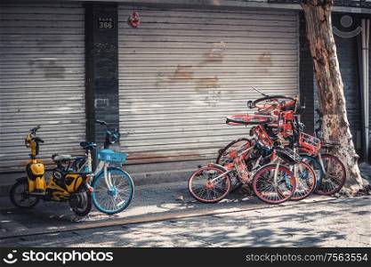 Hangzhou, China - Novemeber 09, 2019: Pile of abandoned broken share electric bicycles on the sidewalk as a result of the bike-share oversupply.. pile of electric bikes on the sidewalk, Hangzhou