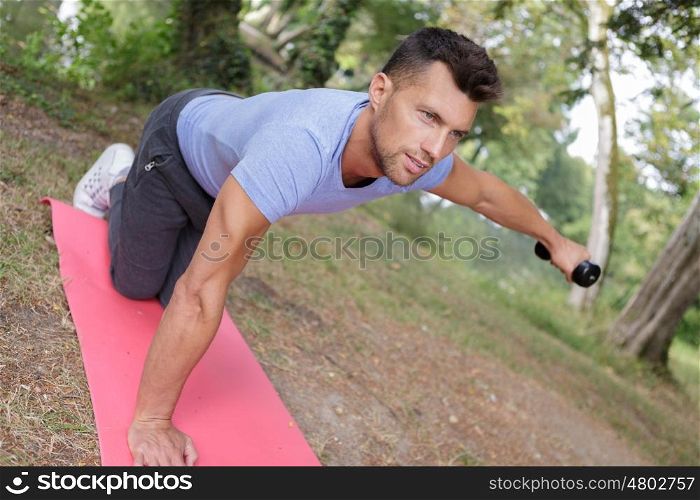 hansome man making exercises on mat outdoors