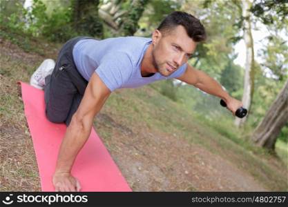 hansome man making exercises on mat outdoors