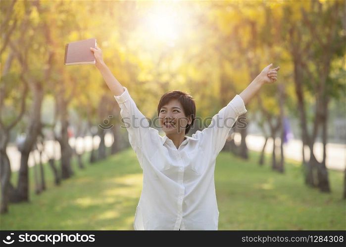 hapiness face of yonger woman and student book in hand standing in summer park
