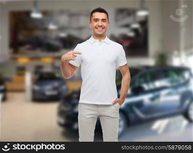 happiness, advertisement, fashion, gesture and people concept - smiling man in t-shirt pointing finger on himself over auto show background