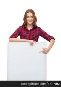 happiness, advertising and people concept - smiling teenage girl pointing finger to white blank board