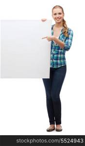 happiness, advertising and people concept - smiling young woman pointing finger to white blank board