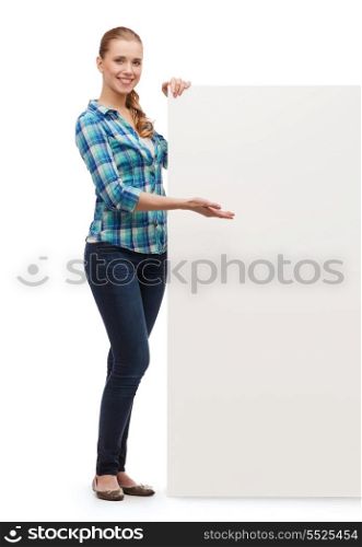 happiness, advertising and people concept - smiling young woman pointing hand white blank board
