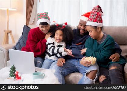 Happiness African family on sofa video call on laptop computer together in the living room at home on Christmas day, new year, vdo call for greeting, parent and daughter contact with family.