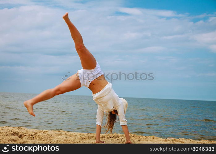 Happiness and craziness. Smiling crazy girl have fun outdoor. Young attractive long haired woman playing on summer beach, doing cartwheel